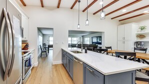 Una cocina moderna con una isla grande, vigas de madera en el techo y vistas al área de comedor.