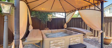 A hot tub with a canopy, stone steps, and a wooden deck.