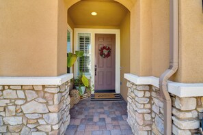 A stone-walled entrance with a door, a welcome mat, and a potted plant. - Near Temecula Wine Country! Socal Home w/ Hot Tub (Winchester)