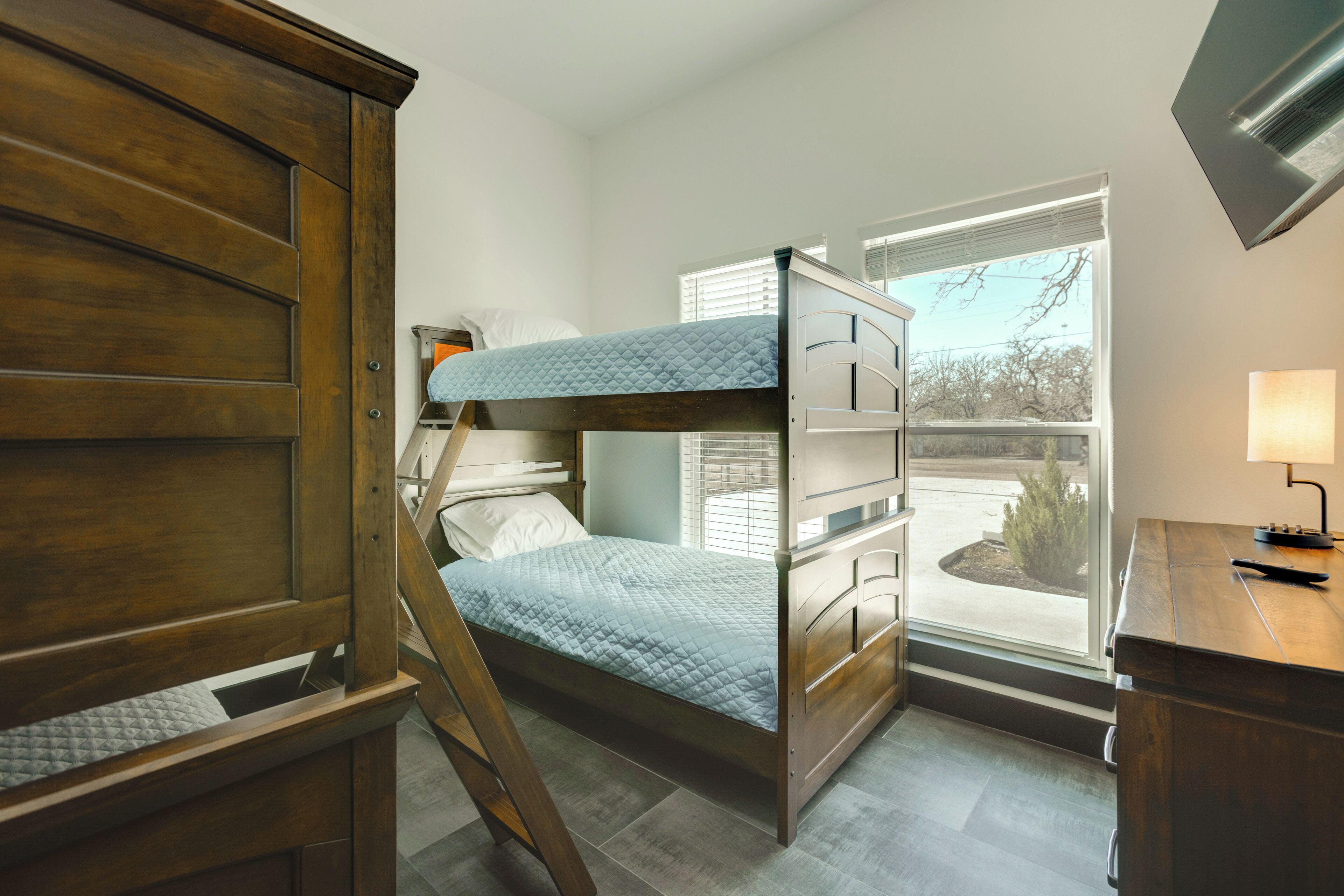 A bunk bed room with a desk and a window.