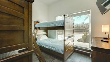 A bunk bed room with a desk and a window.