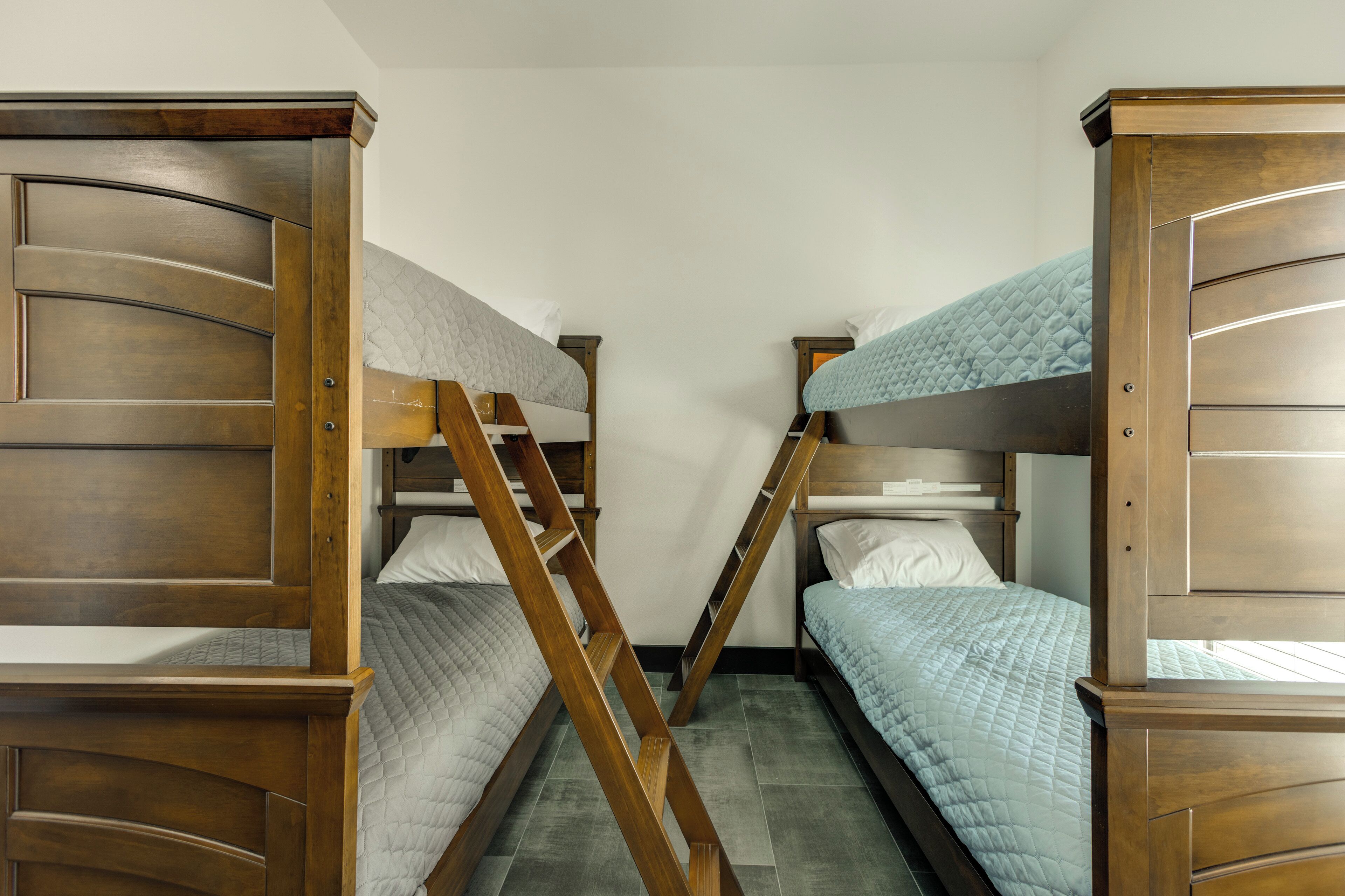 Een kamer met stapelbedden, houten hoofdeinden en een trap.
