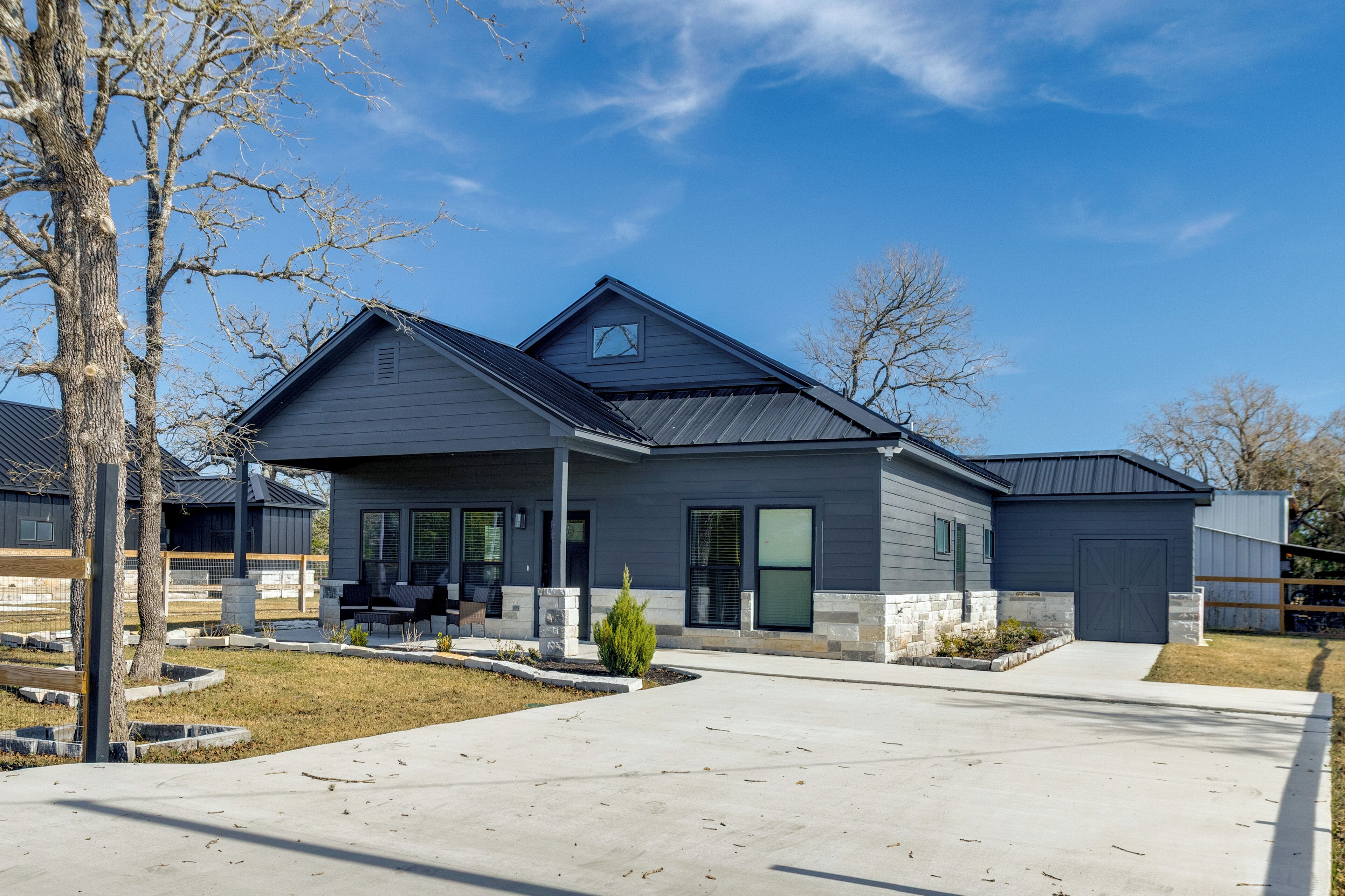 Ein modernes, zweigeschossiges Haus mit überdachter Terrasse, Garage und einem angelegten Vorgarten.