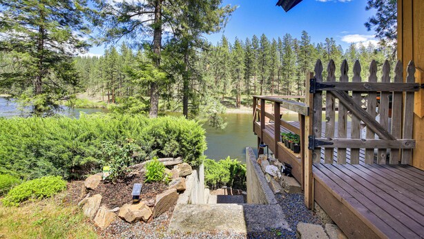 A wooden deck with a stone railing overlooking a pond and forest. - Kettle River Retreat w/ Grill + Outdoor Shower (Kettle Falls)