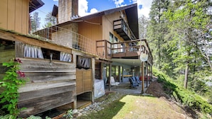 A wooden cabin with a balcony, a covered patio, and a view of the surrounding forest. - Kettle River Retreat w/ Grill + Outdoor Shower (Kettle Falls)