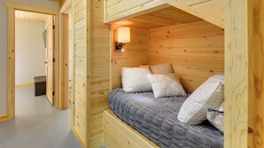A wooden cabin room with a bunk bed, a wall-mounted light, and a small bench. - Kettle River Retreat w/ Grill + Outdoor Shower (Kettle Falls)