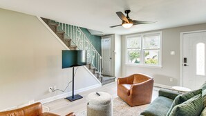 Un salon avec un escalier, un ventilateur de plafond, un téléviseur et des meubles en cuir.