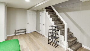 Un escalier avec une rampe, une porte blanche et un banc vert.