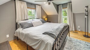 Une chambre à coucher avec un lit, un ventilateur de plafond, une table de chevet et une lampe sur pied.