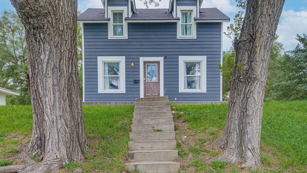 Une maison à deux étages avec une porte d’entrée, un petit porche et un escalier menant à la porte d’entrée.