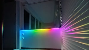 Ein Flur mit einer farbigen LED-Leuchtleiste an der Decke und einer geschlossenen Rolltür.