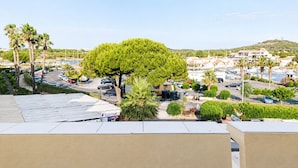Ein Parkplatz mit Autos, einem großen Baum und Gebäuden im Hintergrund.