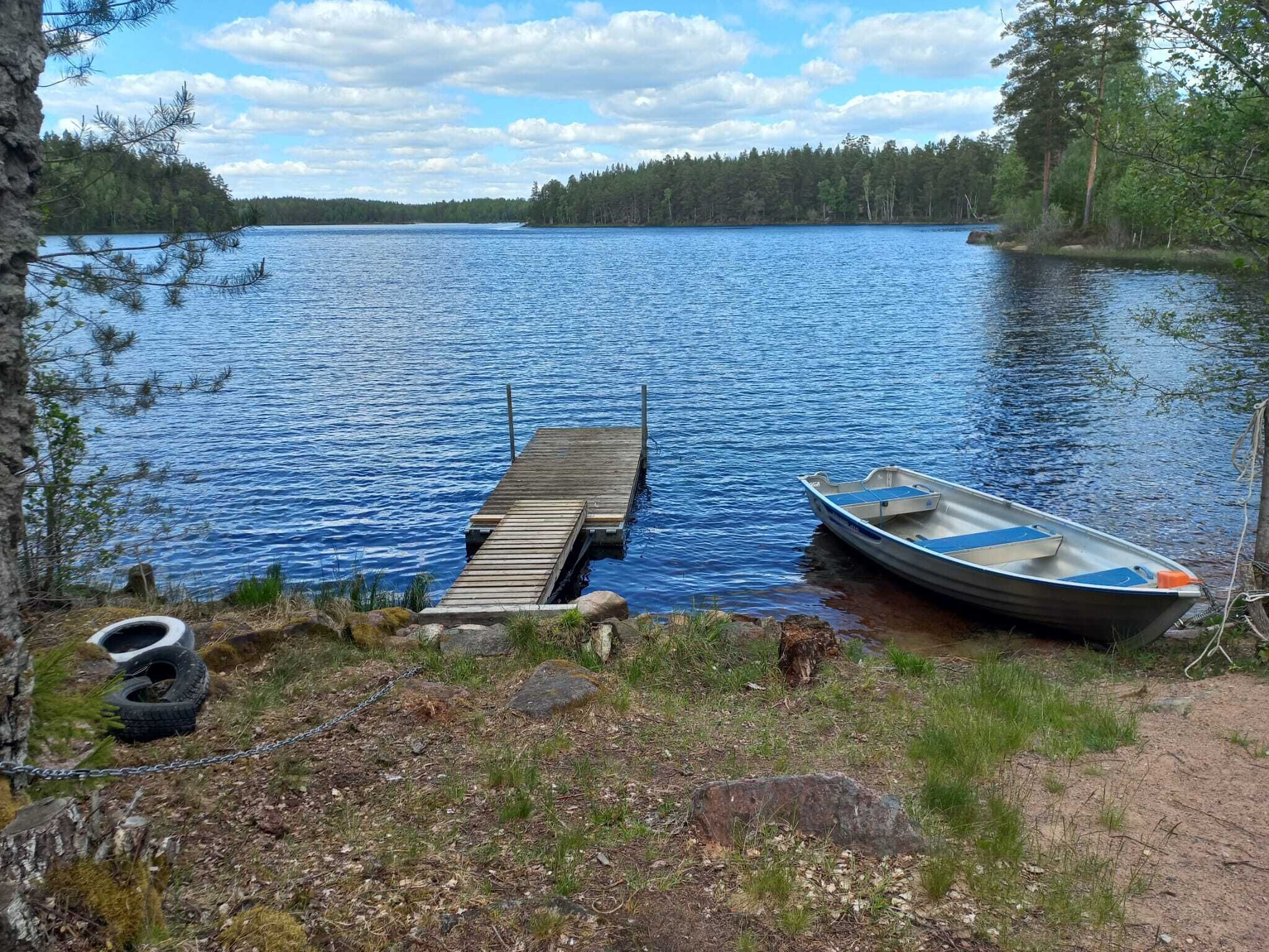 Un lac avec un quai en bois et un petit bateau.
