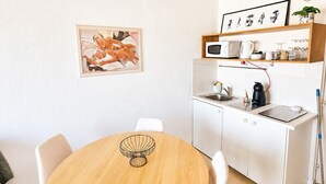 Kompakti keittiö, jossa on valkoiset kaapit, mikroaaltouuni ja vedenkeitin.