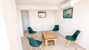 Een moderne kamer met een houten tafel en vier teal-kleurige stoelen, witte muren en twee ingelijste foto's.