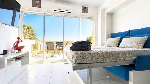 Een moderne slaapkamer met een bed, een bureau en een balkon met uitzicht.