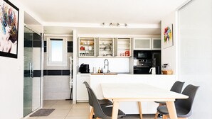 Een moderne keuken met een eethoek, met een groot schiereiland, zwarte stoelen en een witte tafel.