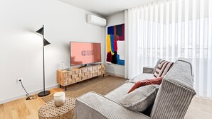Ein modernes Wohnzimmer mit Fernseher, Stehlampe, einem farbenfrohen abstrakten Gemälde und einem Sofa.