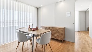 Ein moderner Essbereich mit einem Holztisch, grauen Stühlen und einem Holzschrank.