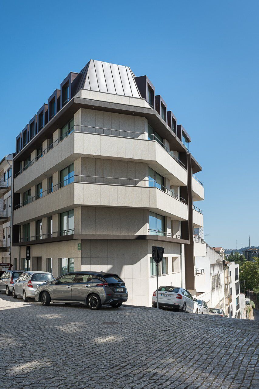 Un edificio de varios pisos con un diseño arquitectónico moderno, con balcones y grandes ventanales.