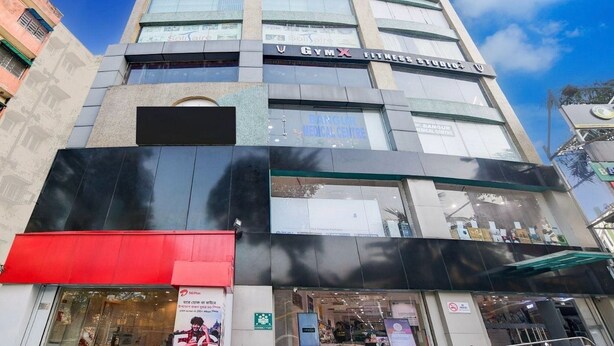 Un edificio de varios pisos con un letrero llamativo que dice 'Gym X Fitness Studio'.