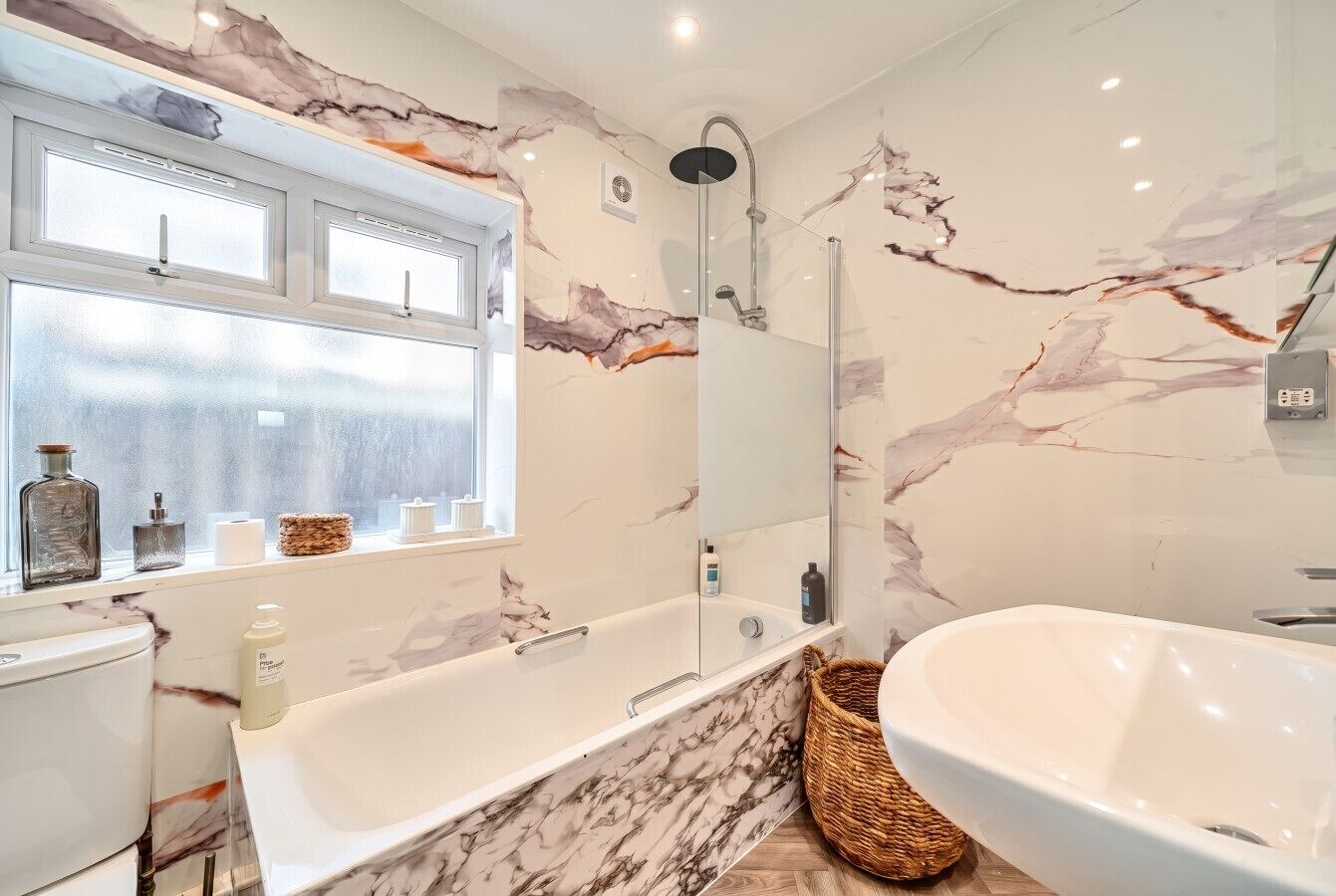 Un baño moderno con tocador de mármol, una bañera independiente, un espejo grande y un ventanal con vistas.