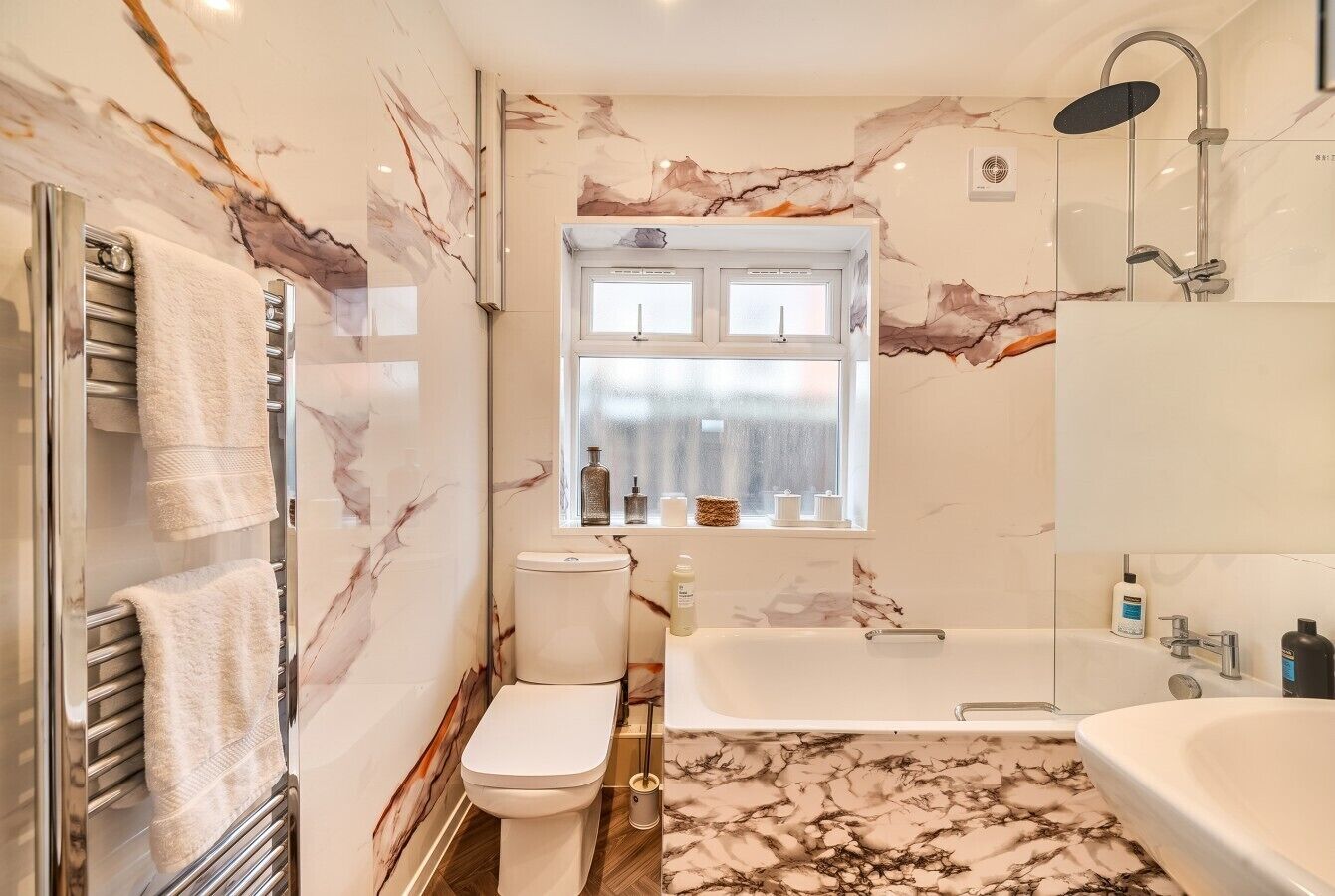Ein Badezimmer mit Marmorboden, Toilette, Badewanne und Dusche.