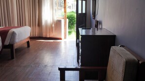 A room with a bed, a desk, a chair, and a large window with curtains.