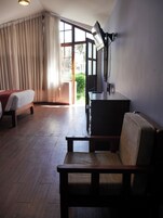 A room with a bed, a desk, a chair, and a large window with curtains.