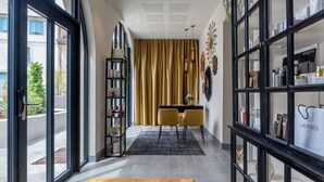 A hotel corridor with a dining area, a black bookshelf, and a view through the glass doors.