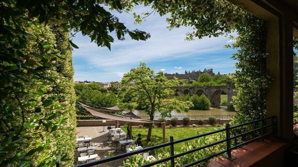 A terrace with outdoor seating overlooking a historic bridge and river.