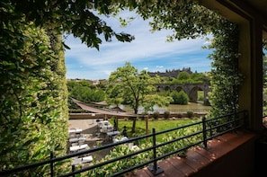 A terrace with outdoor seating overlooking a historic bridge and river.