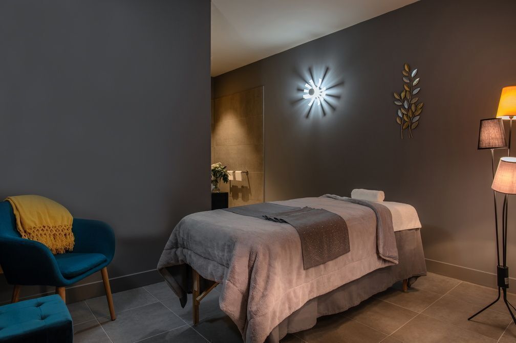 A modern bedroom with a bed, a blue chair, a floor lamp, and wall-mounted decor.