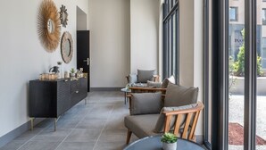 A modern interior with a black console, round mirrors, a sofa, and a dining area.