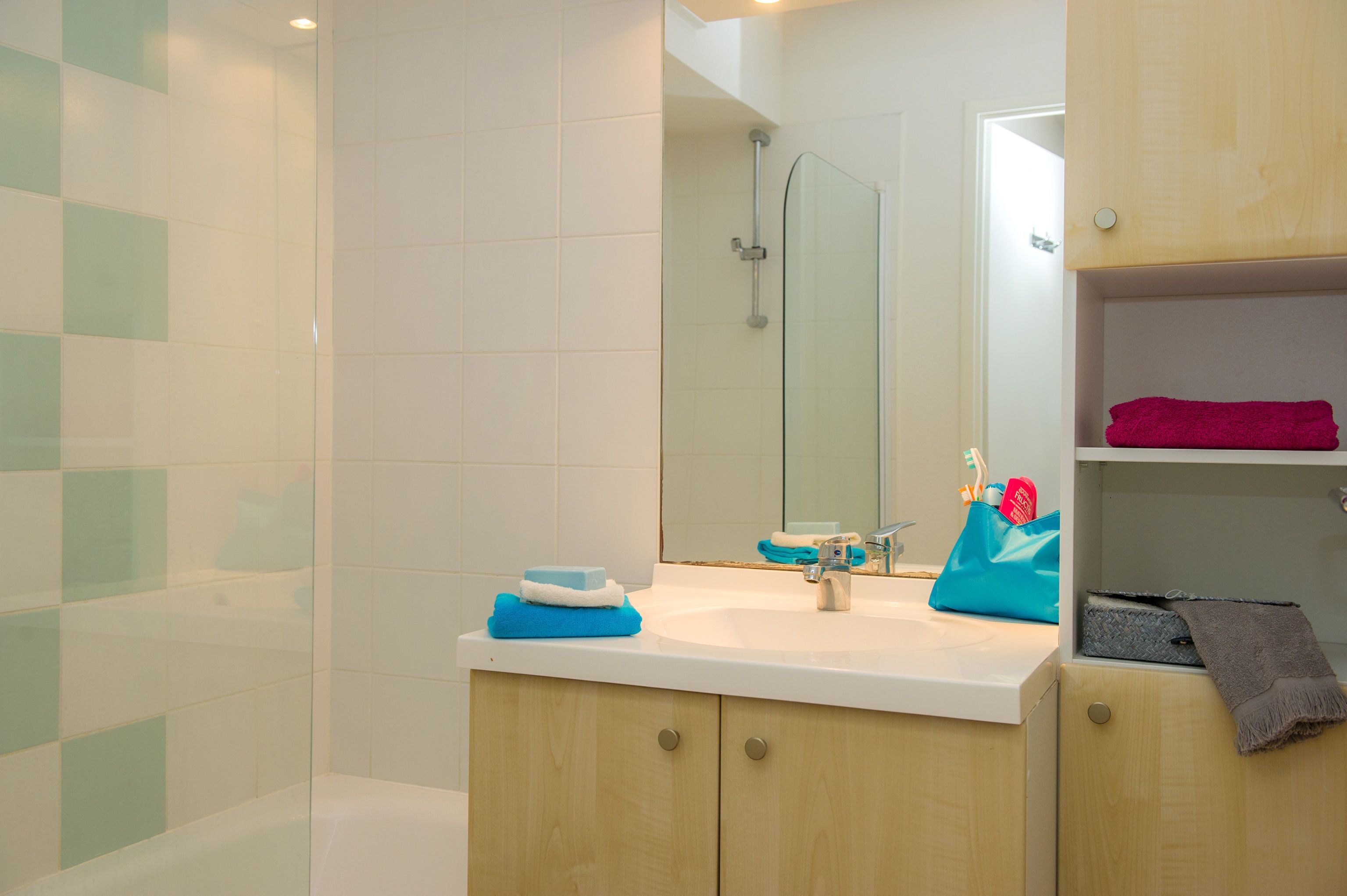 Ein Badezimmer mit Glasdusche, Waschbecken mit Spiegel und Handtuchhalter.