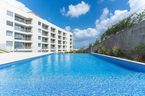 Un edifici modern amb piscina, balcons i un cel serè.