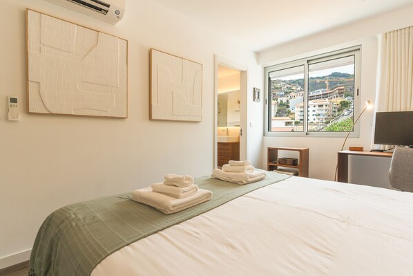 Ein Hotelzimmer mit einem Bett, einem Fenster mit Blick und einer Wand-Klimaanlage.
