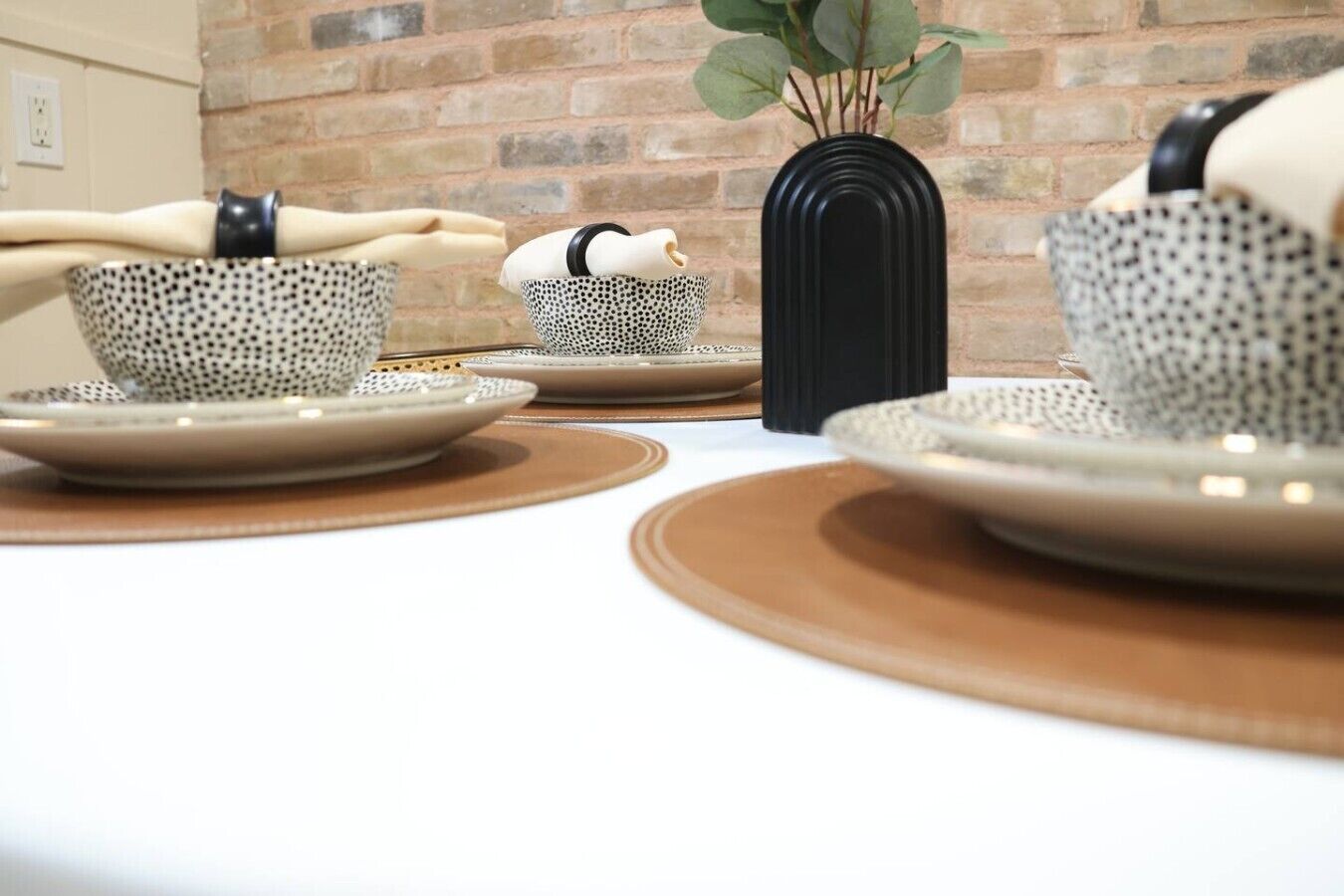 A table set with patterned cups, plates, and a black vase.