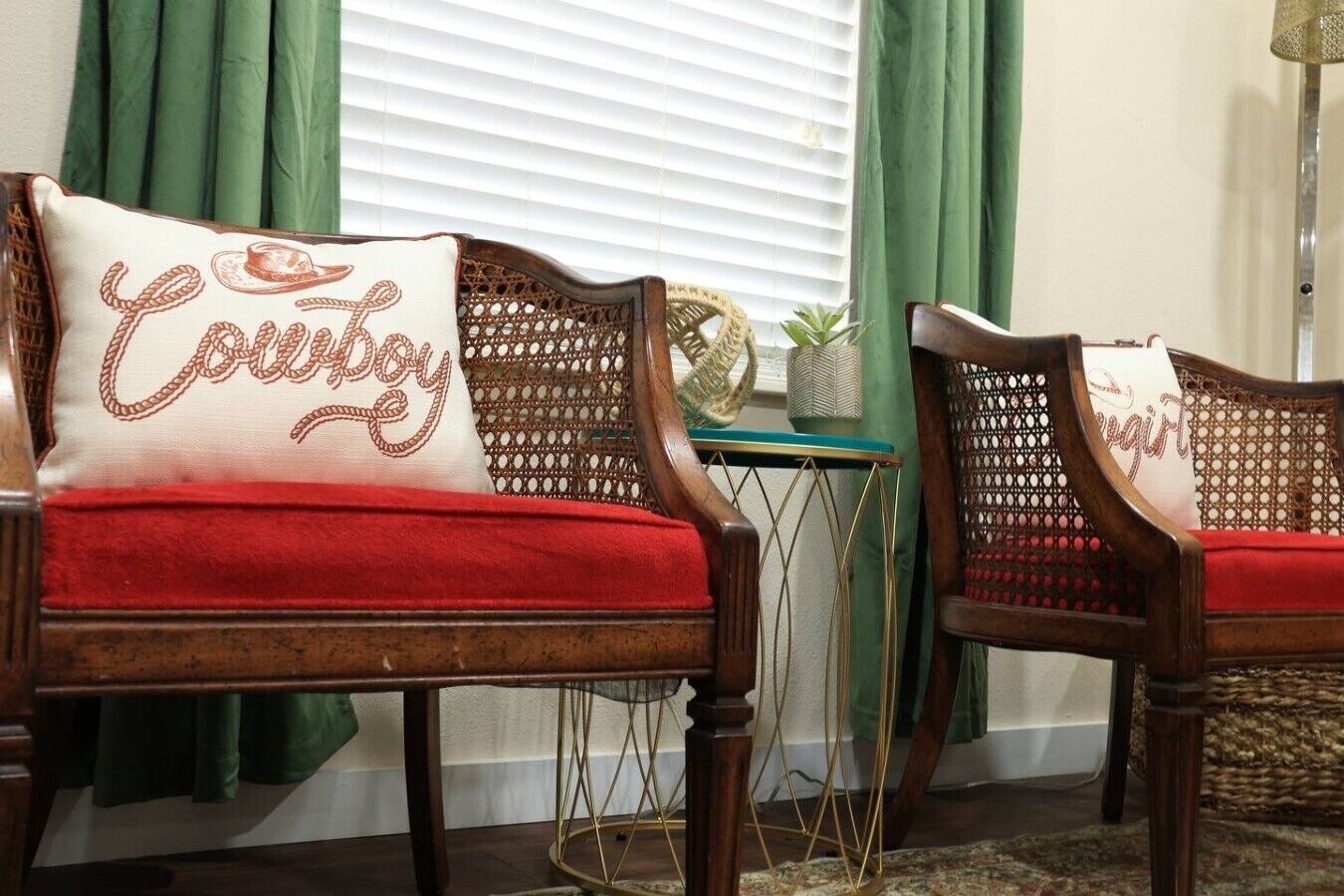 Two wooden chairs with red cushions and a decorative pillow with 'Cowboy' embroidered on it.