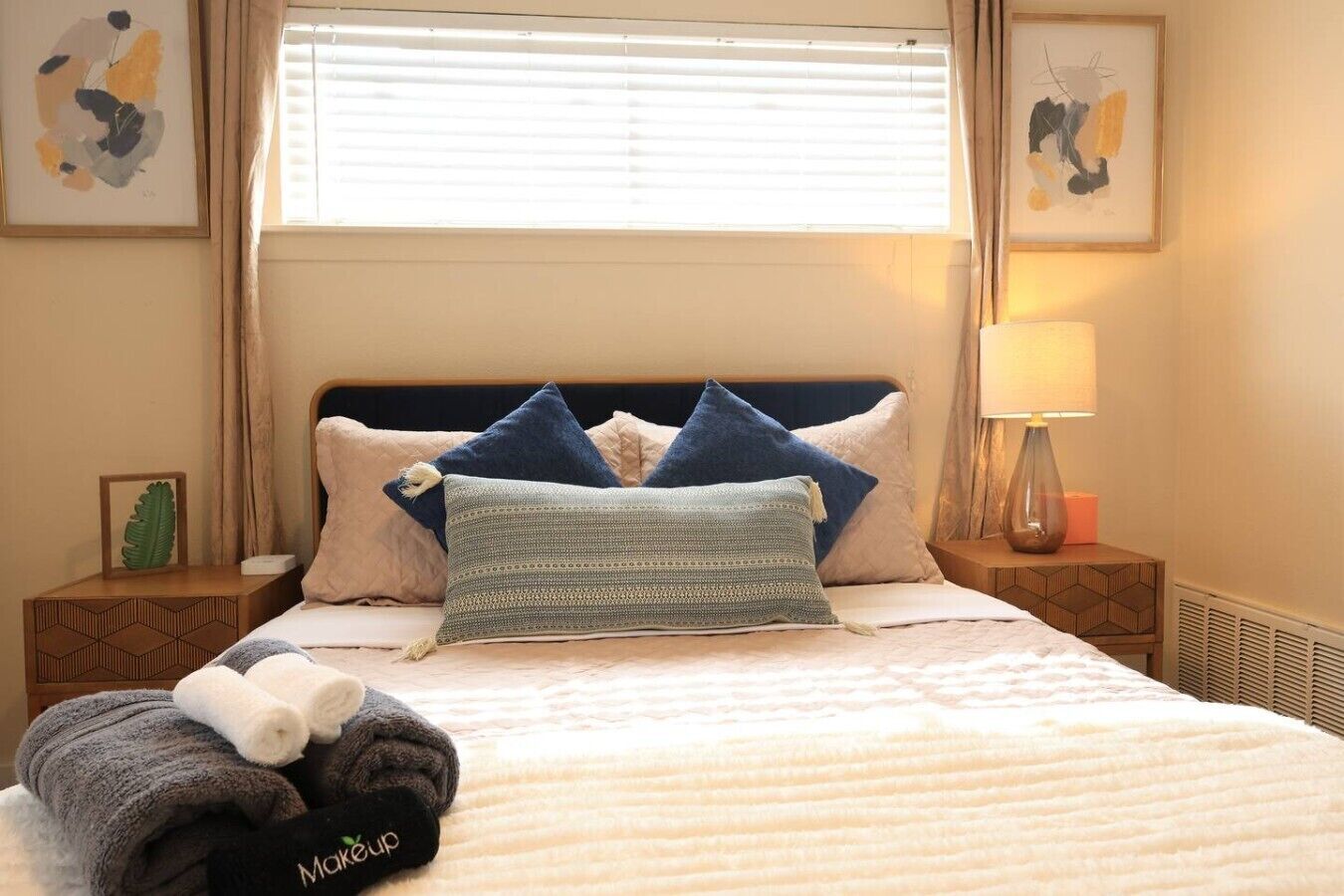 A neatly made bed with a headboard, a bedside lamp, and a framed picture on the nightstand.