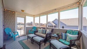 A covered patio with wicker furniture, a view of neighboring houses, and string lights. - Ocean View, Steps to Beach, 8-Person Hot Tub-HGTV Inspired Southern Charm (Avon)