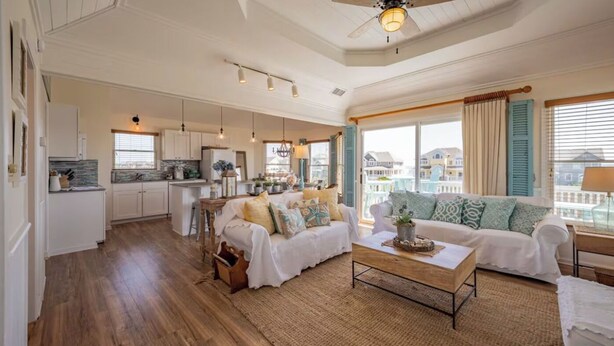 A spacious living area with a sofa, coffee table, and kitchen in the background. - Ocean View, Steps to Beach, 8-Person Hot Tub-HGTV Inspired Southern Charm (Avon)
