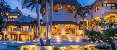 A resort with multiple buildings, outdoor seating, and a well-lit pool area.