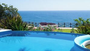 A swimming pool with a view of the ocean, surrounded by greenery and a wooden fence. - An exclusive beach house, perched on a cliff with panoramic ocean views. (Santa María Huatulco)