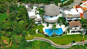 A resort with multiple buildings, a swimming pool, and a thatched-roof structure. - An exclusive beach house, perched on a cliff with panoramic ocean views. (Santa María Huatulco)