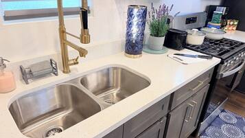 A kitchen with a double sink, stainless steel faucet, and modern appliances.