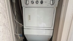 Lavadora y secadora compacta, blanca, de dos puertas, con perillas de control visibles y un cable de alimentación.