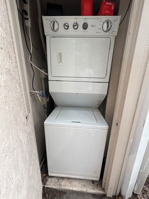 Máquina de lavar e secar compacta, branca, de duas portas, com botões de controle visíveis e um cabo de energia.
