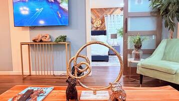 Una sala de estar con televisor de pantalla plana, un adorno decorativo y una revista sobre la mesa de centro.