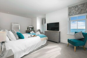 Ein modernes Schlafzimmer mit Bett, Fernseher, Stuhl und Fenster mit Blick.